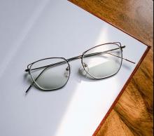 Wireframe glasses lying on a sheet of paper atop of wooden table
