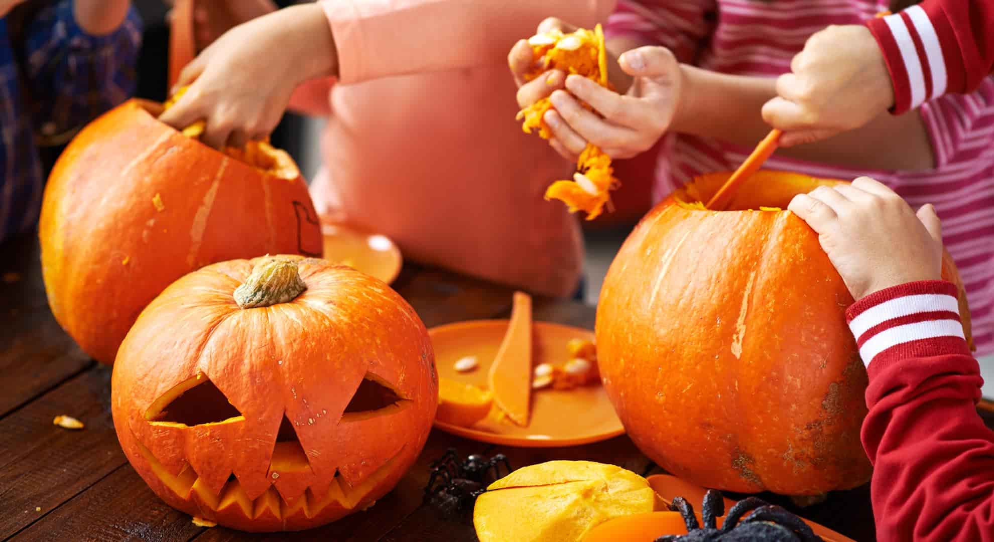 Children carving pumpkins by hand