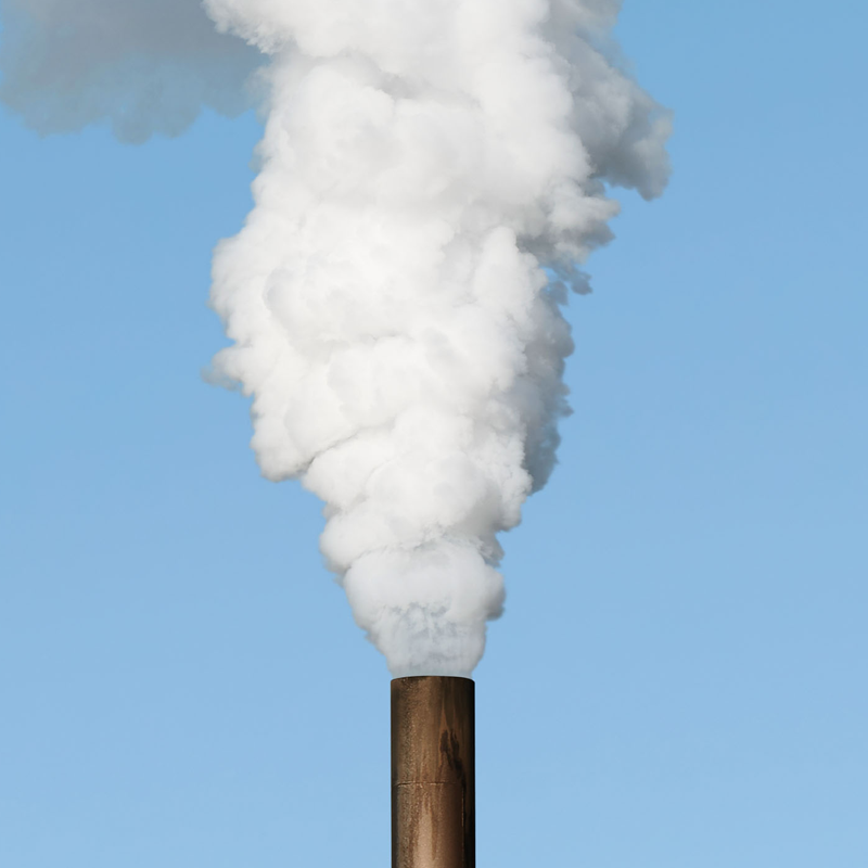 A large chimney releasing a white cloud of smoke