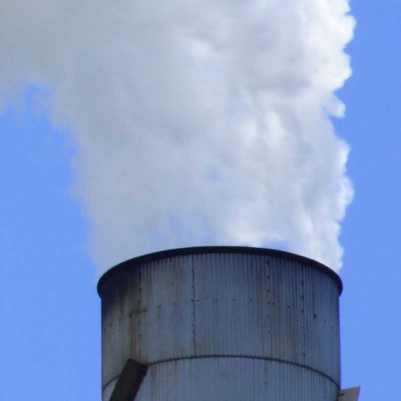 A large chimney releasing a white cloud of smoke
