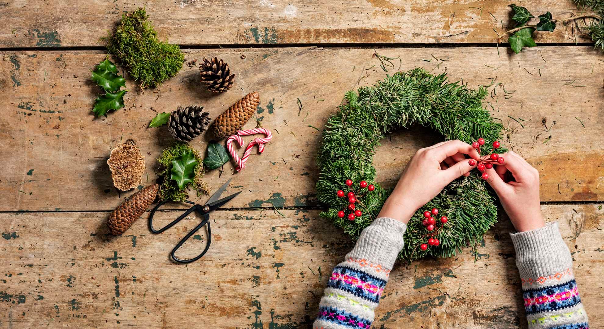 Making a Christmas wreath decoration with tree clippings, berries and pine cones