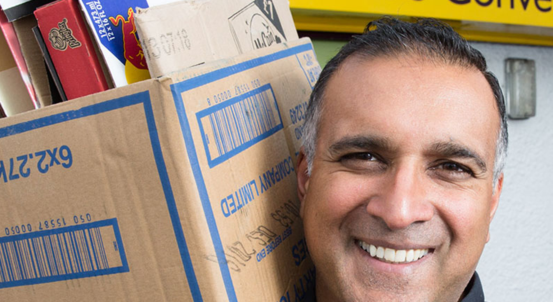A person smiling while holding a cardboard box