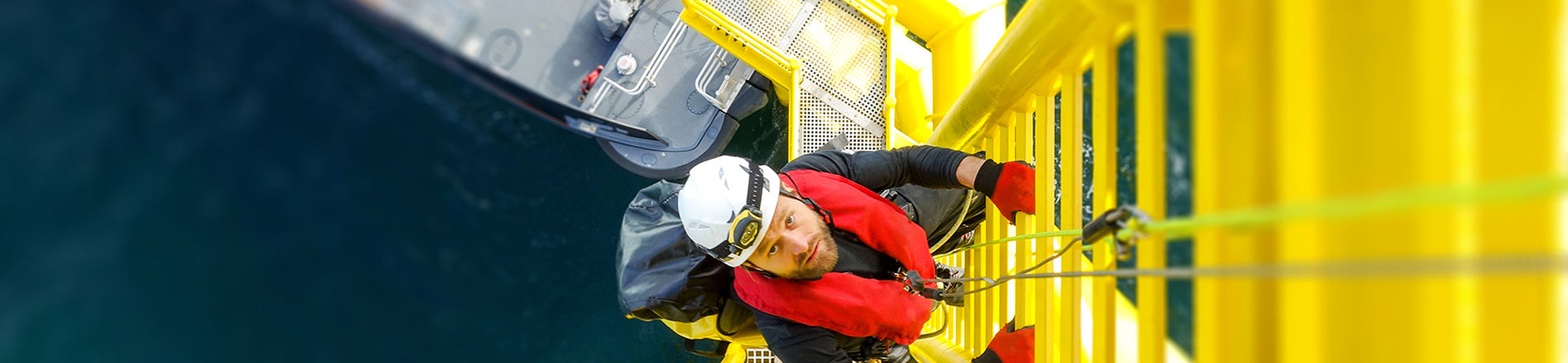 A person climbing a yellow ladder at sea