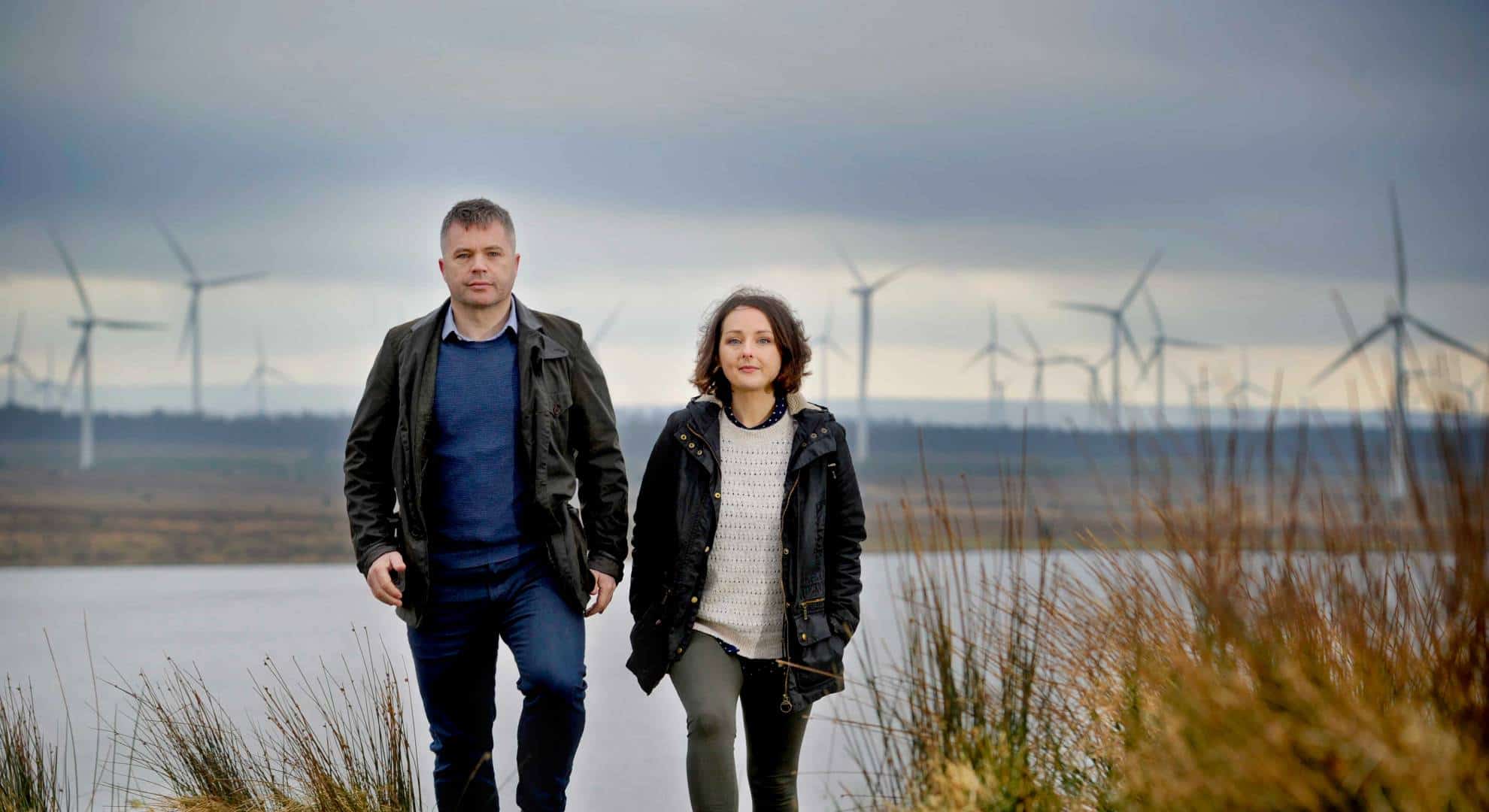 Photo of two people from ReBlade walking outdoors with wind turbines in the background