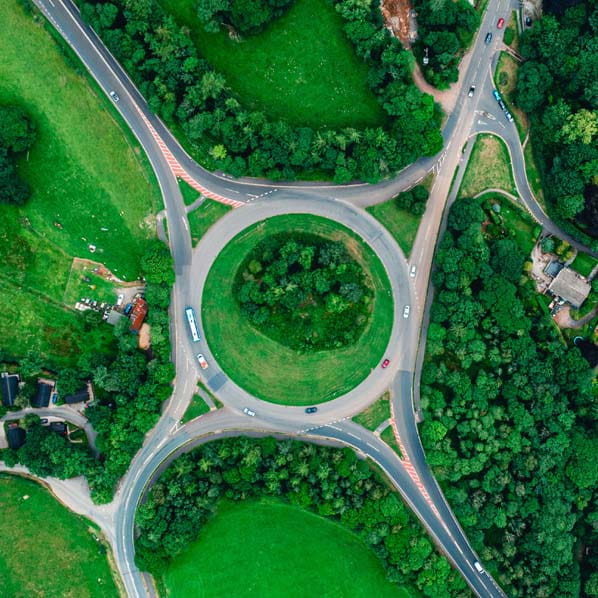 Aerial view photo of a circular roundabout surrounded by green fields trees and houses