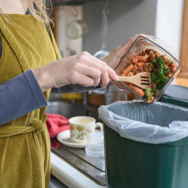 Person recycling food waste in a food caddy