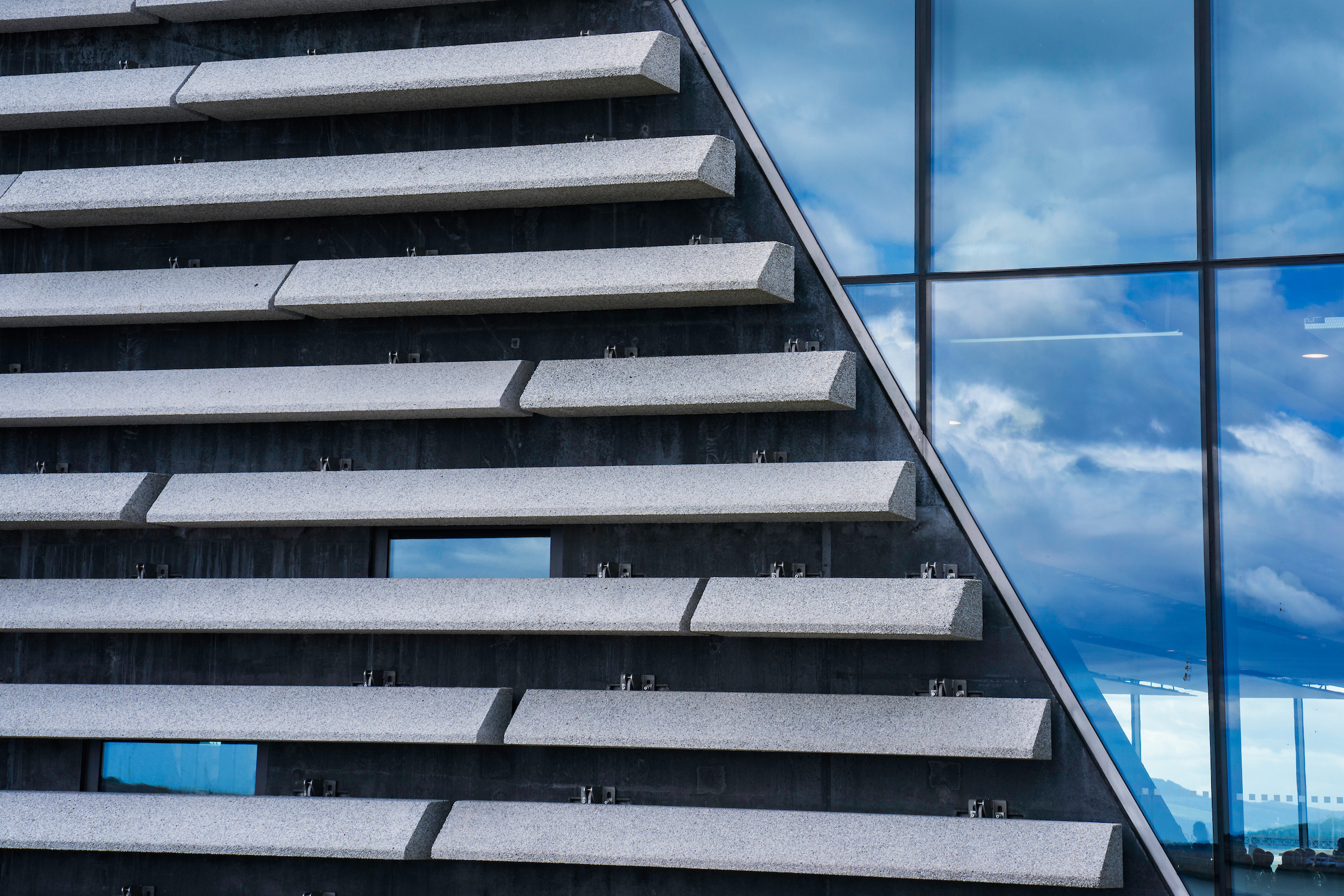 Modern building facade with layered concrete panels and reflective glass windows.